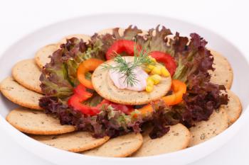 Cream, sweet corn and dill on cracker and vegetables in white plate.