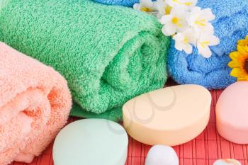 Colorful rolled towels with flowers and soaps closeup picture.
