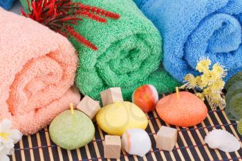 Colorful rolled towels with flowers, candles and stones closeup picture.