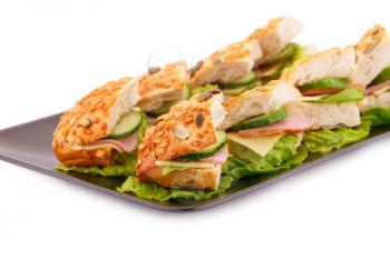 Sandwiches with fresh vegetables, ham and cheese on plate.