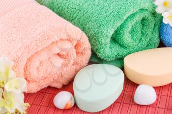 Colorful rolled towels with flowers, soaps and stones closeup picture.