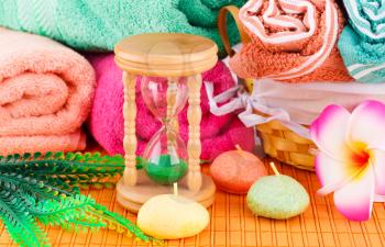 Spa set with colorful towels, candles and sandglass on bamboo background.