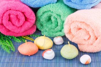 Colorful rolled towels with leaves, soaps and stones closeup picture.