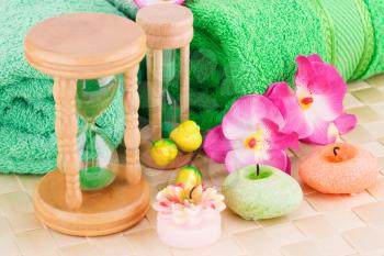 Spa set with towels, candles, sandglasses and flowers on bamboo background.