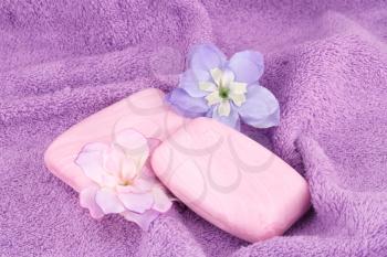 Pink soaps and flowers on towel.