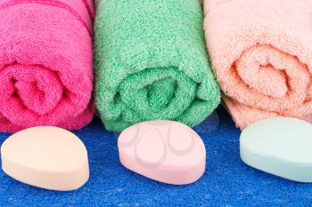 Colorful rolled towels with soaps on plastic background.