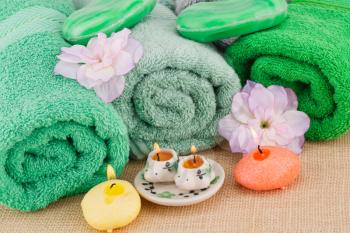 Spa set with towels, candles, soaps and flowers on bamboo background.
