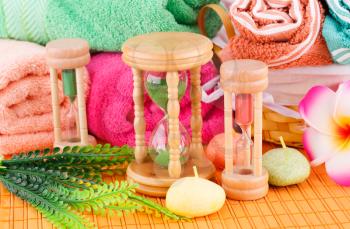 Spa set with colorful towels, candles and sandglasses on bamboo background.