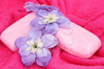 Pink soaps and flowers on red towel.