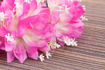 Pink artificial flowers on cloth background, closeup picture.