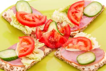 Sandwiches with fresh vegetables and ham on plate.