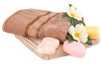 Folded towel, soaps and flowers isolated on white background.