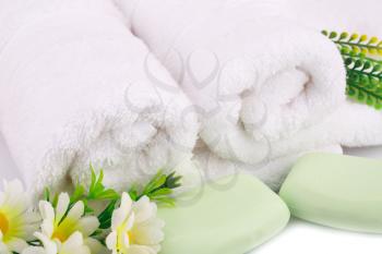White rolled towels with soaps and flowers closeup picture.