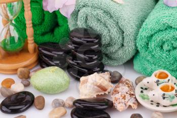 Spa set with towels, candles, shells, sandglass and stones closeup picture.