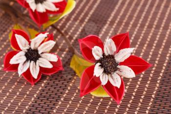 Colorful fabric flowers on bamboo background, closeup picture.