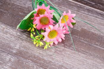 Pink fabric daisies on wooden background.