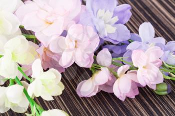 Colorful fabric flowers on striped cloth background.
