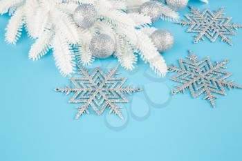 Christmas decoration with gray balls, snowflakes and fir-tree white branch on the blue background.