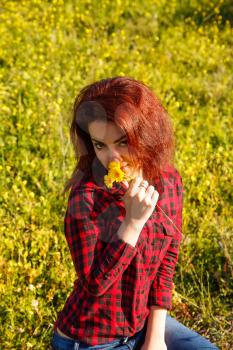 Young pretty woman with yellow daisy flowers in field.