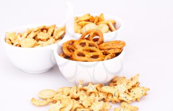 Different salted crackers in bowl isolated on white background.