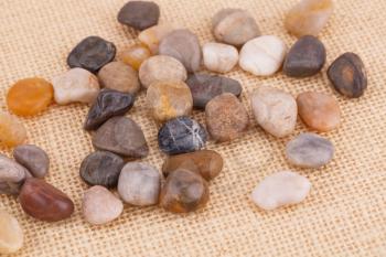 Colorful pebbles on beige fabric background.