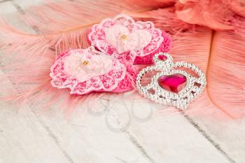 Two pink hearts with lace, jewelry with stone and feathers on gray wooden background.