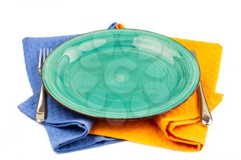 Green empty plate with knife and fork on blue and yellow  cotton towels isolated on white background.
