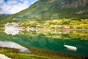 Landscape with mountains, cruise liner, village and fjord in Norway.