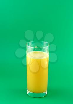 Glass of fresh orange juice with squeeze slice on green background.