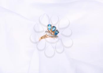Golden Ring with sapphire on white silk.