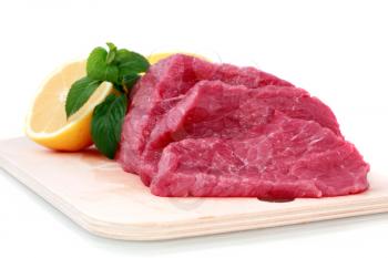 Beef steak  on meat hardboard with green leaf and lemon. Isolated.