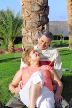 Mature couple lying in embrace and looked at each other with love. In tropical resort.