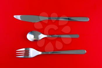 Table serving-knife,plate,fork on  red colour background.