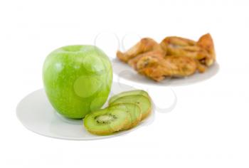 Opposition-healthy meal apples and kiwi, or unhealthy meal on background- roast chiken. Isolated