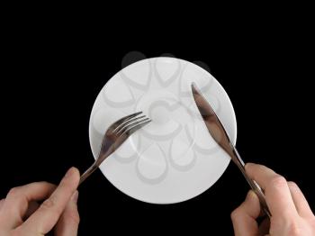 Table serving-knife, fork in hands on colour background.
