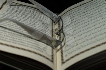 pages of holy koran and glasses