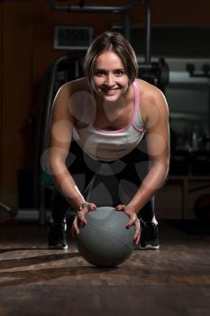 Attractive Female Athlete Performing Push-Ups On Medicine Ball