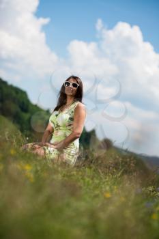young woman in dress sitting on the grass