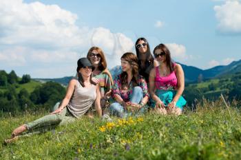 group of girls sitting on grass and having fun
