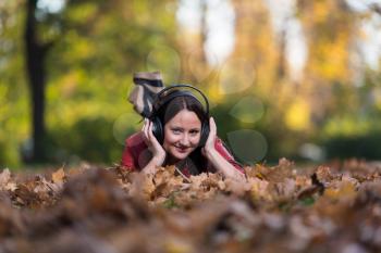 Young Girl With Headphones Enjoying Music In Autumn