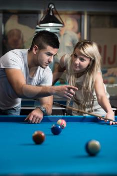 Man Teaching Woman How To Play Pool