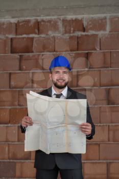 Portrait Of Construction Master With Blue Helmet And Blueprint In Hands