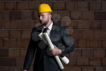 Portrait Of Construction Master With Yellow Helmet And Blueprint In Hands