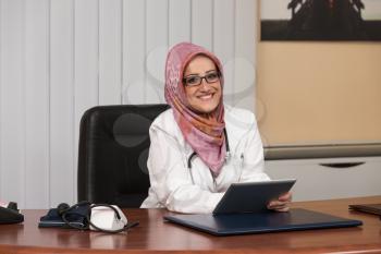 Muslim Doctor Working On Touchpad In Office