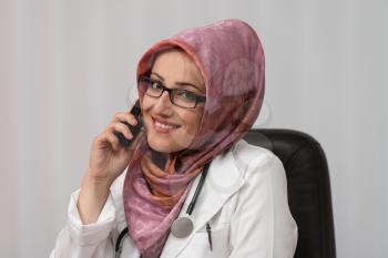 Muslim Doctor Working At Her Computer While Talking On The Phone