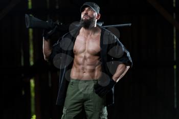 Action Hero Muscled Man Holding Machine Gun - Standing In Abandoned Building Wearing Green Pants