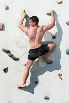 Young Man Climbs Up An Outdoors Rock Wall - He Is Clearly Determined To Make It To The Top