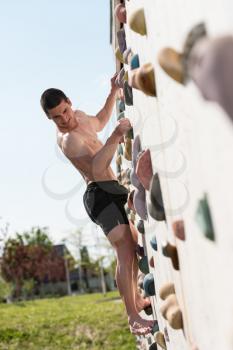 Young Man Climbs Up An Outdoors Rock Wall - He Is Clearly Determined To Make It To The Top
