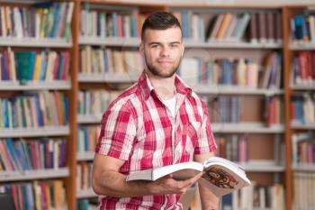 In The Library - Handsome Male Student With Books Working In A High School - University Library - Shallow Depth Of Field