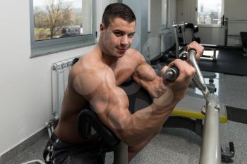 Young Athlete Doing Heavy Weight Exercise For Biceps On Machine